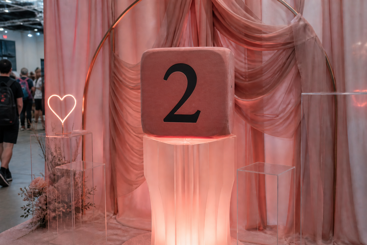 Dado foam grande face 2 em pedestal acrílico rosa-suave, drapes chiffon blush e arco metal rose-gold.